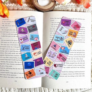 Puede incluir: Un conjunto de marcadores coloridos con diferentes géneros de novelas románticas impresos en ellos. Los marcadores tienen forma de sellos postales y presentan ilustraciones de corazones, libros y otros símbolos románticos.