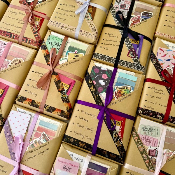 Könnte beinhalten: Eine Sammlung rechteckiger Buchpakete, eingewickelt in braunes Papier, zusammengebunden mit bunten Bändern und gemustertem Klebeband. Jedes Paket enthält handschriftliche Genre-Notizen und dekorative Aufkleber.