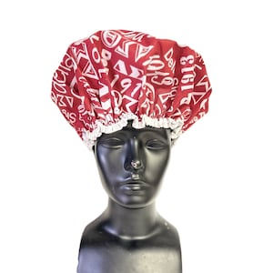 May include: A red shower cap with a white print of numbers and symbols. The cap is on a black mannequin head.