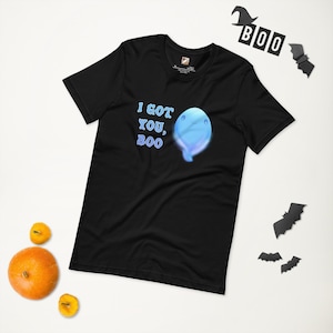 Puede incluir: Camiseta negra con el texto "I GOT YOU, BOO" y un gráfico de fantasma azul. La imagen incluye decoraciones de Halloween y calabazas, ideal para la temporada de sustos.