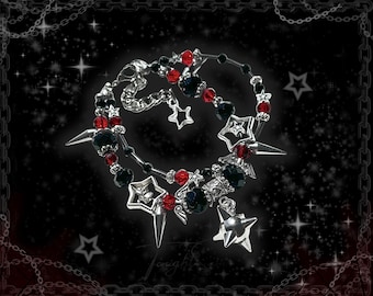 May include: A gothic-style necklace with a black background and star accents. The necklace features silver-toned metal, black and red beads, and star-shaped pendants. The design includes spikes and a chain border.