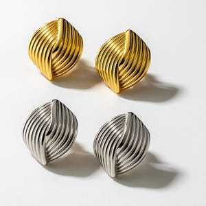Può includere: Due paia di orecchini a lobo. Un paio è color oro e l'altro color argento. Ogni orecchino ha un design unico a coste, con un accento verticale centrale. Gli orecchini sono esposti su sfondo bianco.