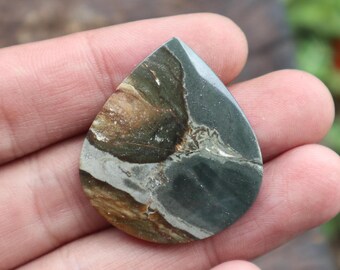 May include: A teardrop-shaped cabochon of green, brown, and white jasper. The stone has a swirling pattern and a smooth, polished surface.