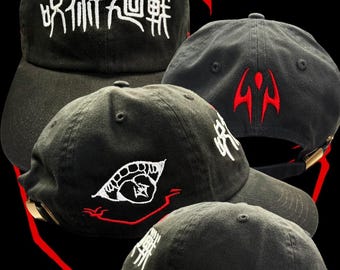 May include: Black Sukuna Cap with white and red embroidered designs. The cap features Japanese characters and a stylized eye. The text "Sukuna Cap" is visible. The cap has a curved brim and adjustable strap.