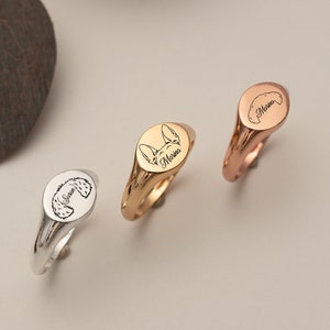 Op de afbeelding: Drie ovale zegelringen met gepersonaliseerde gravures. De ringen zijn van zilver, goud en roségoud. De gravures bevatten de namen "Marina", "Zus" en "Feniks".