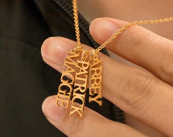 May include: Gold necklace with four vertical nameplate charms. The names on the charms are "Abbey", "Patrick", "Maggie", and "Abby".