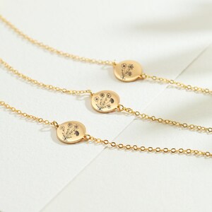 May include: Three gold necklaces with delicate chains and round pendants featuring a floral design.
