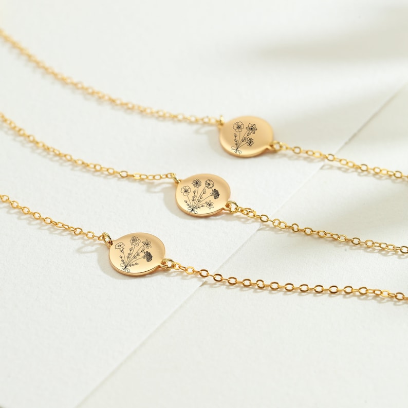 May include: Three gold necklaces with delicate chains and round pendants featuring a floral design.