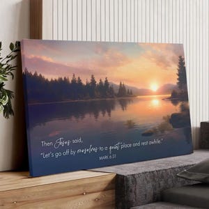 May include: Canvas art print featuring a serene lake scene at sunset. The artwork displays a vibrant sky with orange and purple hues, reflecting on the water. Text reads, "Let's go off by ourselves to a quiet place and rest awhile." MARK 6:31.