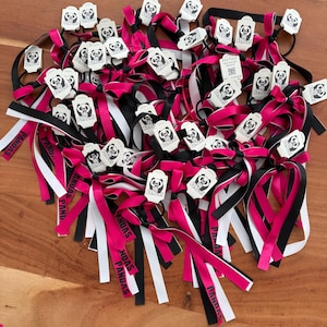 Può includere: Una collezione di elastici per capelli con nastri sovrapposti in rosa acceso, nero e bianco. Ogni elastico è fissato a un cartoncino rettangolare bianco stampato con un'illustrazione di panda e il testo PANDAS. Alcuni nastri riportano la parola PANDAS.