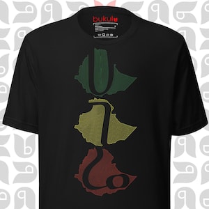 Op de afbeelding: Zwart T-shirt met een afbeelding van de omtrek van Ethiopië in rood, geel en groen. De afbeelding is verticaal gestapeld met de rode omtrek onderaan, de gele omtrek in het midden en de groene omtrek bovenaan.