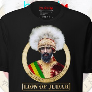 May include: Black t-shirt with a gold circle featuring a portrait of a man wearing a white fur hat and a gold and red robe. The text "LION OF JUDAH" is printed in gold below the circle.