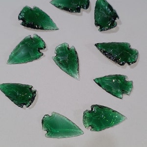 May include: Ten green arrowhead-shaped glass pieces with a translucent, mottled appearance.