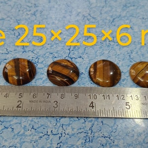 May include: Five round tiger's eye cabochons measuring 25 mm by 25 mm by 6 mm, lined up on a ruler.