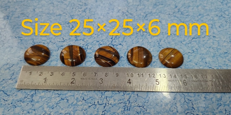 May include: Five round tiger's eye cabochons measuring 25 mm by 25 mm by 6 mm, lined up on a ruler.