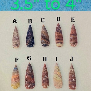 Könnte beinhalten: Zehn handgefertigte Pfeilspitzen mit einzigartigen Mustern und Farben werden gezeigt. Die Pfeilspitzen sind zwischen 8,9 und 10,2 cm lang. Die Sammlung umfasst verschiedene Brauntöne, Rot, Blau und Creme.