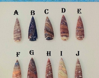 May include: Ten handcrafted arrowheads, each with unique patterns and colors, are displayed. The arrowheads range from 3.5 to 4 inches in length. The collection includes various shades of brown, red, blue, and cream.