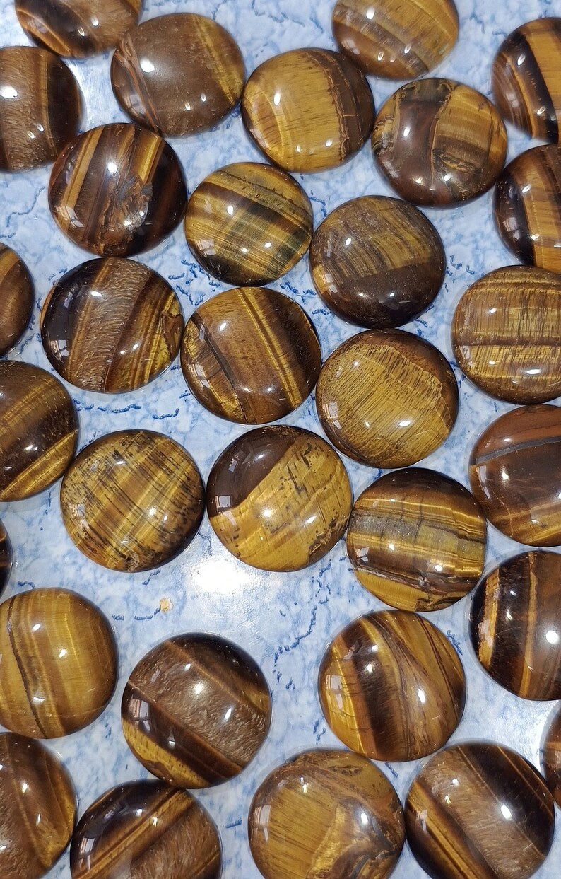 May include: A collection of polished tiger's eye stones, each with a unique pattern of brown, gold, and black stripes. The stones are smooth and glossy, with a slightly rounded shape.