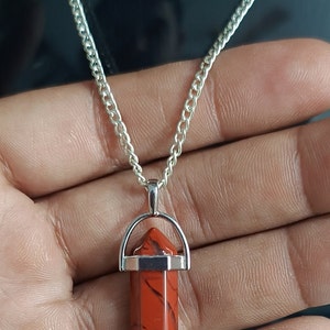 May include: A silver chain necklace with a red jasper point pendant. The pendant is set in a silver bezel and has a silver bail.