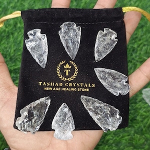 以下が含まれることがあります： タシャクリスタルズニューエイジヒーリングストーンの文字が入った黒いベルベットポーチに入った、透明なクォーツの矢じり7本。