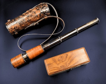 May include: A brass telescope with a leather carrying case and a wooden box. The telescope has a brown leather covering and a brass body. The carrying case is decorated with a floral pattern. The wooden box is brown and has a wood grain pattern.