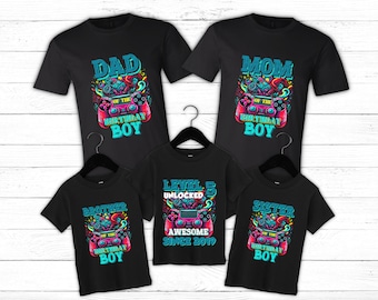 May include: A set of five black t-shirts with a video game theme. The shirts feature the text "Dad of the Birthday Boy", "Mom of the Birthday Boy", "Brother of the Birthday Boy", "Sister of the Birthday Boy", and "Level 5 Unlocked Awesome Since 2019".