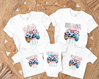 May include: Set of five white t-shirts with a video game controller graphic and text that reads "Dad of the Birthday Boy", "Mom of the Birthday Boy", "Brother of the Birthday Boy", "Sister of the Birthday Boy", and "Level 10 Unlocked Awesome John".