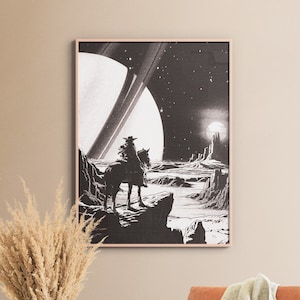以下が含まれることがあります： 白黒の額入りアートプリント。宇宙の風景の中で馬に乗ったカウボーイが描かれています。惑星とリングが特徴で、レトロなSFスタイルです。リビングルームや寝室に適しています。