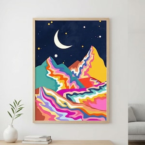 May include: A framed art print featuring a colorful mountain landscape under a dark blue night sky. The artwork showcases a crescent moon, stars, and vibrant, wavy patterns in shades of pink, orange, yellow, and teal. The frame is a light wood color.