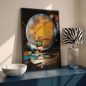 May include: A framed wall art print featuring a surreal scene of a Holiday Inn sign and a swimming pool set against a large, glowing orange planet in space. The artwork displays a retro aesthetic with a dark sky, a pool, and a neon sign.