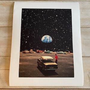 May include: A vintage car parked in a deserted lot with a view of Earth in the night sky. The car is black with a white roof and a license plate that reads "52 1346". A person in a red shirt stands next to the car.