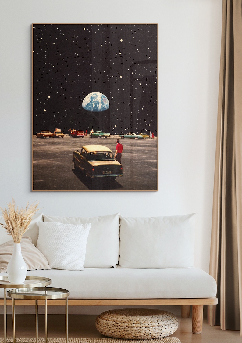 May include: A retro-style collage artwork featuring a group of people standing in a parking lot on the moon, looking up at Earth in the sky. The artwork is framed in a brown wood frame.
