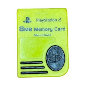 May include: A neon green 8MB memory card for PlayStation 2. The card features the PlayStation logo, the text "PlayStation 2", "8MB Memory Card", and "MAGICGATE". A black oval with the "nyko" logo is on the bottom right.
