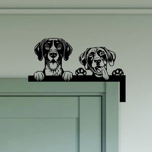 May include: Black and white silhouette of two German Shorthaired Pointers peeking over a door frame. The dogs are looking at the viewer with their tongues out.