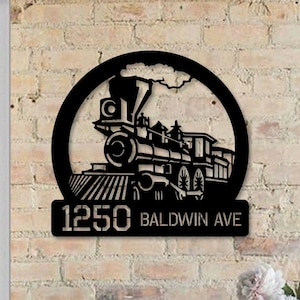 May include: Black metal house number sign with a steam engine design. The sign reads "1250 Baldwin Ave".