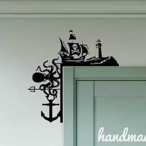 May include: Black and white silhouette wall decal featuring a pirate ship, octopus, anchor, and lighthouse. The decal is mounted on a white wall next to a light green door.