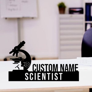 May include: Black and white silhouette of a microscope with the text "CUSTOM NAME SCIENTIST" on a white surface.