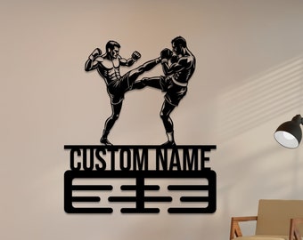 May include: Black metal wall art featuring two figures in a fighting pose. The art includes a space for a custom name and a series of lines for displaying medals or awards.