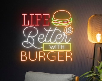 May include: A neon sign featuring the text LIFE Better IS WITH BURGER in red, white, and yellow light. The sign includes a stylized orange and green burger graphic. The text is arranged in four lines with a mix of block and script lettering styles.