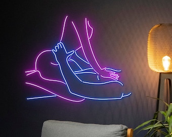 Pode incluir: Uma placa de néon que representa duas figuras em um abraço romântico. A placa é iluminada com néon rosa e azul, criando uma estética vibrante e moderna.