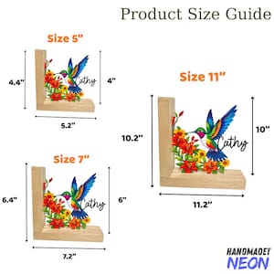 May include: Wooden bookends with a hummingbird design, the name "Cathy", and floral accents. Available in three sizes: 5" (11.2cm x 10.2cm), 7" (16.3cm x 15.2cm), and 11" (25.4cm x 26cm). The bookends are labeled "HANDMADET NEON".
