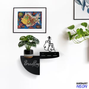 May include: Black metal shelf with a curved front edge. The shelf has a black metal boxing glove design and a chalkboard area that says "Bradley".
