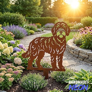 Op de afbeelding: Een roestkleurige metalen tuinsteker met een uitgesneden silhouet van een hond met warrig haar. De hondfiguur is afgebeeld in een staande profielpositie met gedetailleerde vachttexturen en is gemonteerd op een pin voor in de grond.