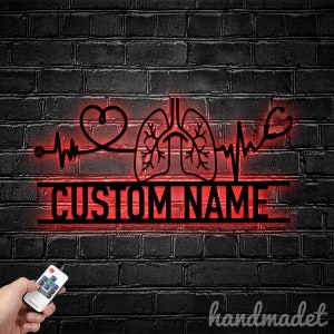 May include: Red LED light sign with a heart, lungs, and a stethoscope with a heartbeat line. The sign says "CUSTOM NAME" in black.