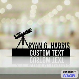 May include: A black laser-cut sign featuring a telescope on a tripod. The sign includes the name "RYAN G. HARRIS" and the words "CUSTOM TEXT" in white. The sign is displayed on a white surface with a blurred background.