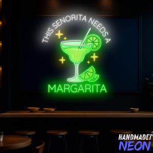 May include: A neon sign with the text "THIS SENORITA NEEDS A MARGARITA" in white and green. The sign features a margarita glass with a lime slice and star accents. The sign is mounted on a dark wall.