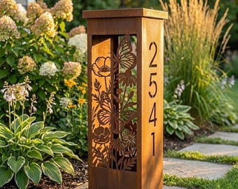 May include: A rectangular, rust-coloured metal address pillar featuring laser-cut designs of butterflies and flowers on the front panel. The side panel displays the vertical house number 2541 in a clean, modern, sans-serif font.