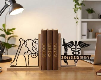 Puede incluir: Soportes para libros de metal negro con temática médica. Uno presenta un diseño esquelético de cadera y pierna, el otro tiene un símbolo de caduceo y la palabra "ORTHOPEDIST". Tres libros marrones se sostienen entre los sujetalibros.