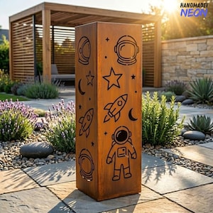 Könnte beinhalten: Eine rechteckige, verwitterte Metall-Außenskulptur mit ausgeschnittenen Weltraum-Designs. Das Design umfasst Astronautenhelme, Raketen, Sterne und Halbmonde. Die Skulptur trägt den Text "HANDMADET NEON".