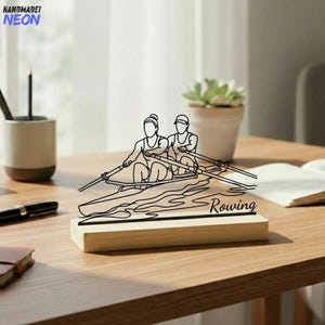May include: A black neon sign showing two people rowing a boat, with the word "Rowing" at the base. The sign is mounted on a wooden base. The sign is on a wooden table.
